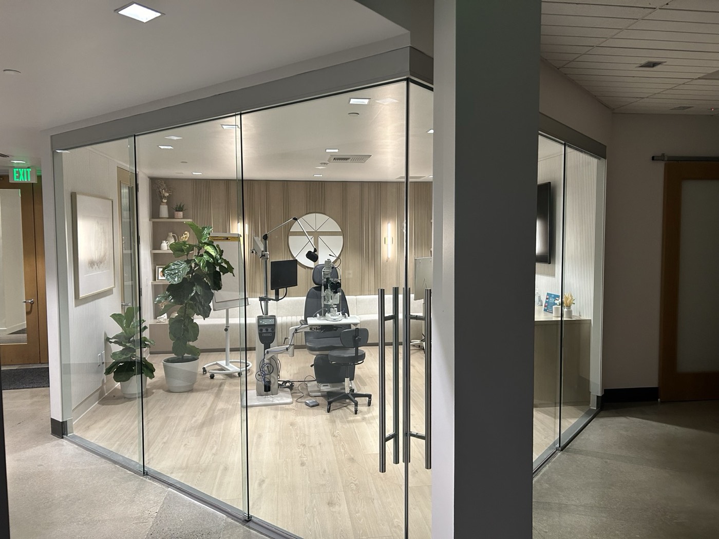 Glass-enclosed clinical suite with wood flooring and consult chairs, Tarsus corporate office buildout