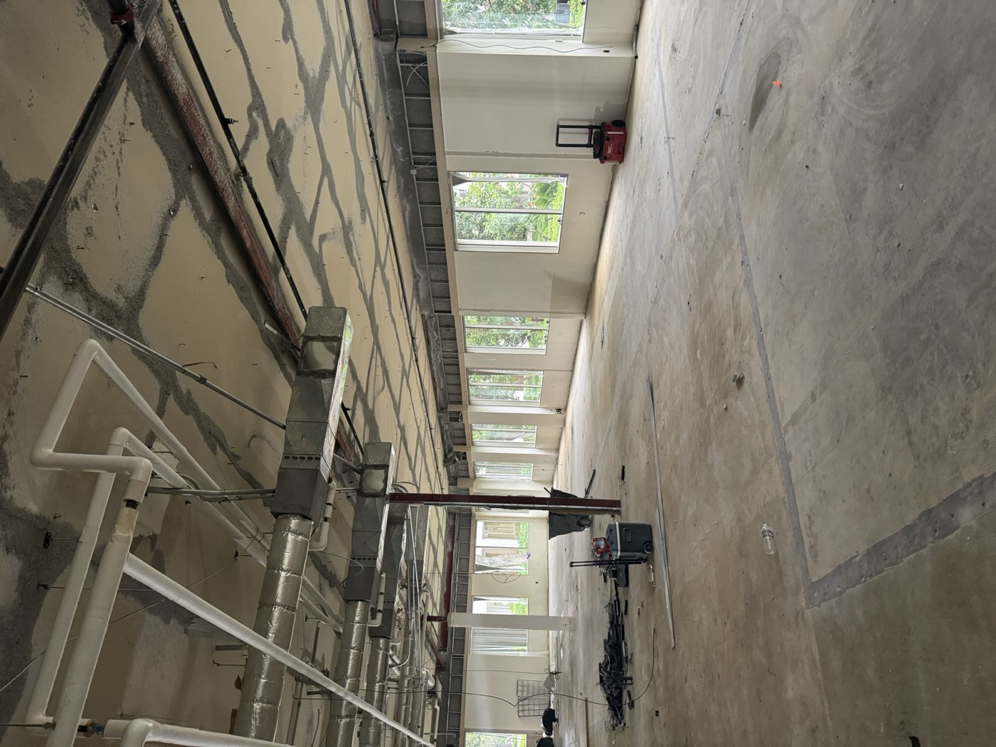 Open white-box shell space with exposed ceiling and large storefront windows, ready for tenant improvement